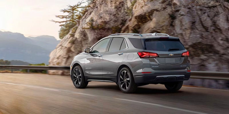 Gray SUV driving on a mountain road with rocky cliffs nearby